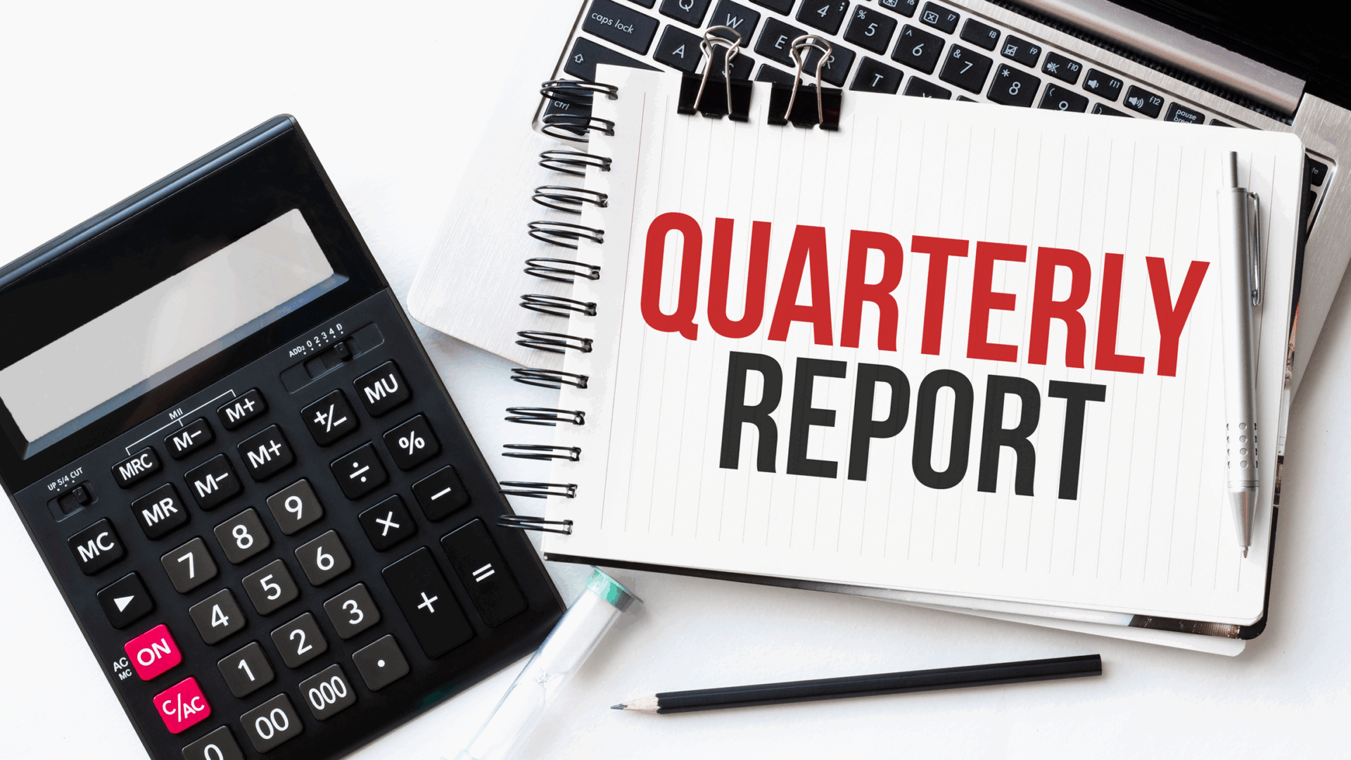 Quarterly report with calculator and laptop