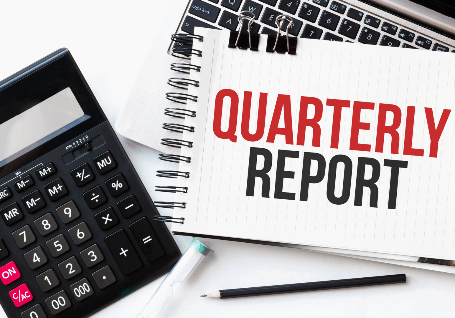 Quarterly report with calculator and laptop